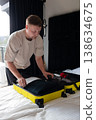 Man packing yellow suitcase on bed preparing for travel 138634675