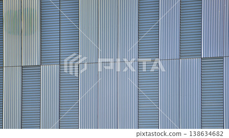 The futuristic building has engineered vertical cladding steel frame panels. The exterior wall of a contemporary commercial style building with aluminum metal composite panels. The futuristic building has engineered vertical cladding steel frame panels. The exterior wall of a contemporary commercial style building with aluminum metal composite panels. 138634682