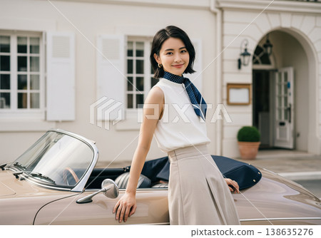 一位優雅的女士，圍巾隨風飄揚，站在一輛老爺車旁。 138635276