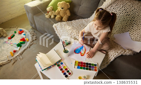 Top view little girl painting heart with watercolor on paper at small table. Top view little girl painting heart with watercolor on paper at small table. 138635531