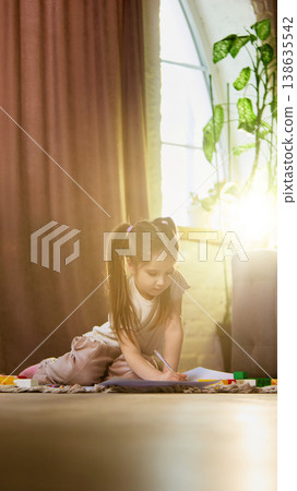 Child drawing on paper with sunlight flare in cozy living room environment 138635542