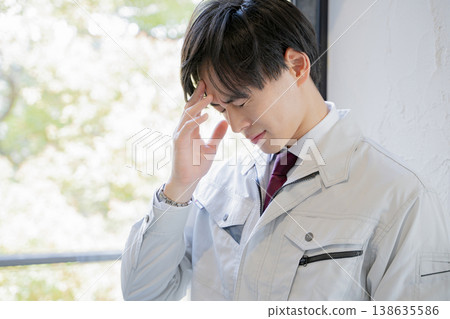 一名身穿工作服的男子雙手抱頭——商業 138635586