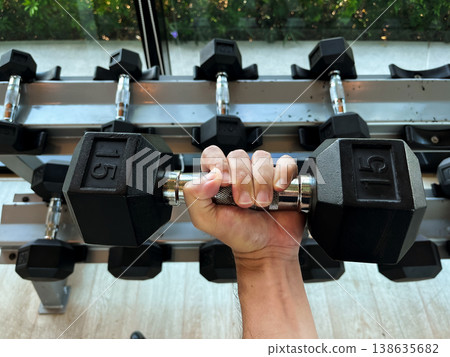 hand gripping dumbbell in gym, representing strength training, fitness workout, muscle building, determination, healthy lifestyle, exercise routine, and motivation for active living 138635682