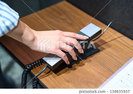 Close-up of a woman's hands as she places an internal phone down at the office reception desk. 138635937