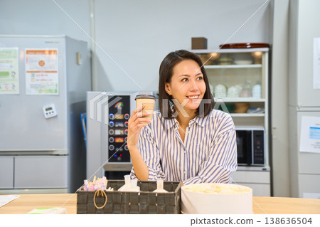 A businesswoman takes a coffee break in the break area between working on her laptop. 138636504