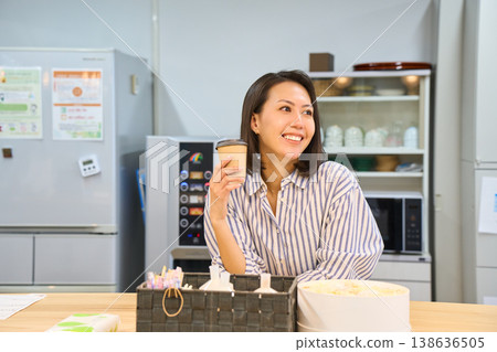 A businesswoman takes a coffee break in the break area between working on her laptop. 138636505