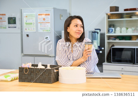 A businesswoman takes a coffee break in the break area between working on her laptop. A businesswoman takes a coffee break in the break area between working on her laptop. 138636511