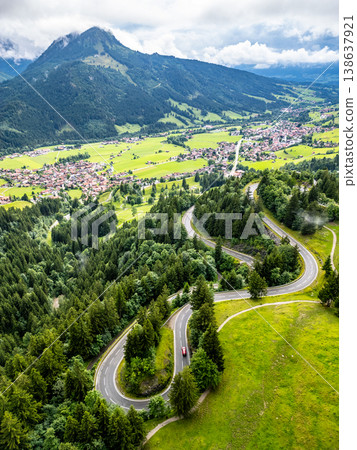 A stunning aerial view captures the winding serpentine roads of the Alps, surrounded by lush green hills and mountain peaks. Ideal for adventure seekers and road trip enthusiasts. A stunning aerial view captures the winding serpentine roads of the Alps, surrounded by lush green hills and mountain peaks. Ideal for adventure seekers and road trip enthusiasts. 138637921