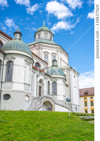 St. Lorenz Basilica features stunning baroque architecture, set against a vivid blue sky. The basilica is located in Kempten, Bavaria, surrounded by lush green lawns. 138637928