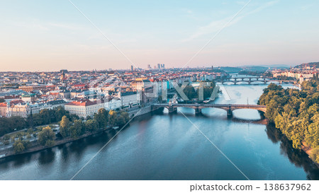 Aerial view of the Vltava River winding through Prague at sunset, showcasing the National Theatre. Diverse architecture and lively atmosphere reflect the city's charm and history. 138637962