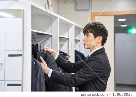 A young businessman hanging his coat in an office locker; a scene of arriving at and leaving work. 138638023