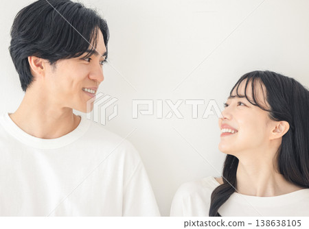 一對年輕情侶在白色背景前深情對視。 138638105