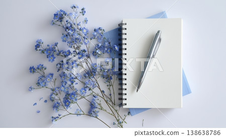 白色書桌上放著打開的筆記本和鋼筆，還有藍色的花。 138638786