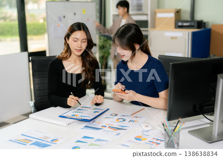 Asian people collaborate on project analysis with financial graphs. Strategic teamwork and insights drive company growth and success. 138638834