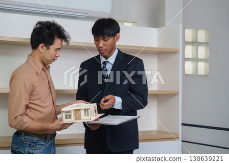 Real estate agent explaining house model to client in office 138639221