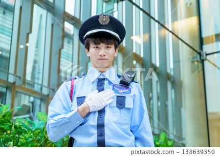 A young Japanese male security guard places his hand on his chest. Photo courtesy of Denpa Gakuen Educational Foundation, Tokyo Electronics College. A young Japanese male security guard places his hand on his chest. Photo courtesy of Denpa Gakuen Educational Foundation, Tokyo Electronics College. 138639350