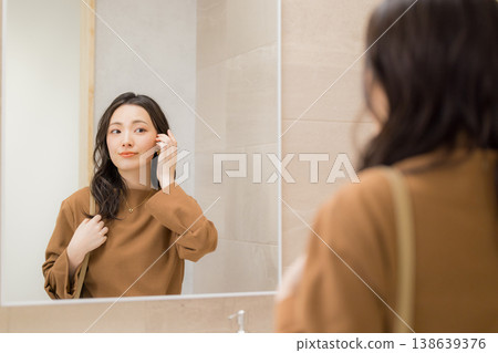 Young woman checking her skin condition in the bathroom Young woman checking her skin condition in the bathroom 138639376