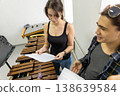 A young man and woman studying a musical score together in a bright rehearsal room at dawn. 138639584