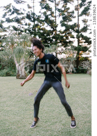 Energetic Young Man Jumps with Joy on Green Lawn 138639624