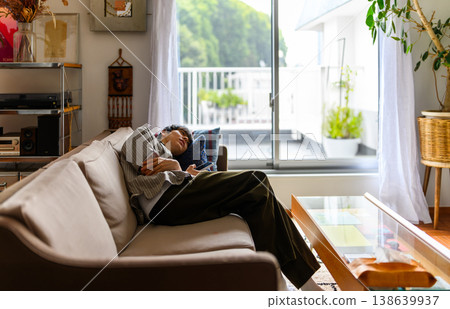 A man dozing off on a sofa. 138639937