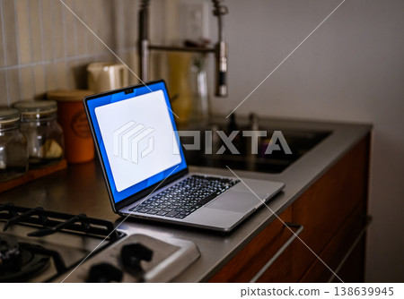 A blank laptop screen opened in the kitchen. 138639945