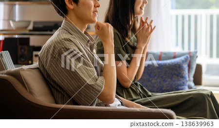 一男一女側臉凝視著沙發上的某樣東西。 138639963