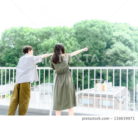 A young man and woman pointing from the rooftop 138639971