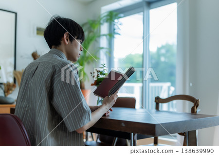 A man engrossed in reading in a brightly lit room. A man engrossed in reading in a brightly lit room. 138639990