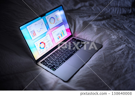 床上放著一台打開的筆記型電腦。 138640008