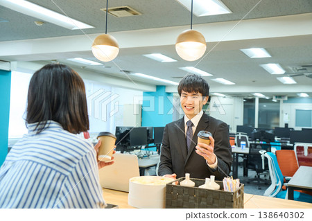一名男員工在辦公室咖啡廳一邊喝咖啡一邊與同事聊天。 一名男員工在辦公室咖啡廳一邊喝咖啡一邊與同事聊天。 138640302