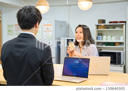 一位微笑的女商人正在辦公室休息室與一位男同事愉快地聊天。 一位微笑的女商人正在辦公室休息室與一位男同事愉快地聊天。 138640305