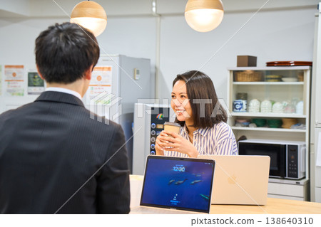 一位微笑的女商人正在辦公室休息室與一位男同事愉快地聊天。 一位微笑的女商人正在辦公室休息室與一位男同事愉快地聊天。 138640310