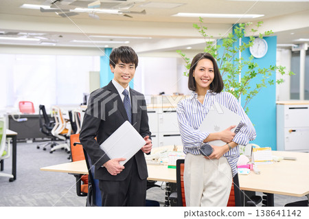 一群面帶笑容的商務人士,男女老少,手持筆記型電腦,在燈光明亮的辦公室裡排成一排。 一群面帶笑容的商務人士,男女老少,手持筆記型電腦,在燈光明亮的辦公室裡排成一排。 138641142