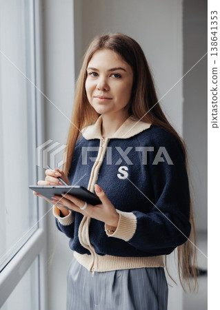 Young female interior designer working on digital tablet with stylus, planning home renovation project by the window. Young female interior designer working on digital tablet with stylus, planning home renovation project by the window. 138641353