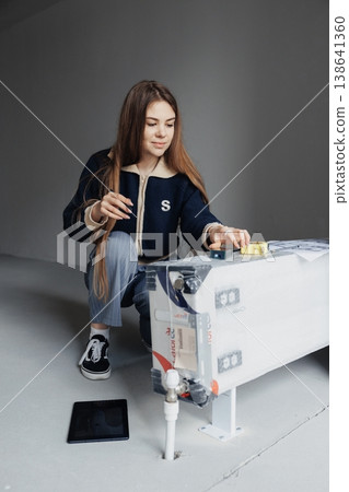 Female interior designer measuring wall with yellow tape measure in a minimalist empty room during renovation. Female interior designer measuring wall with yellow tape measure in a minimalist empty room during renovation. 138641360