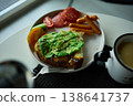Enjoying avocado toast with coffee and sides at a cozy cafe in the morning light 138641737