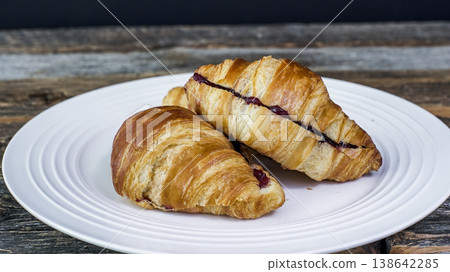 Two croissants filled with chocolate are arranged on a white plate Two croissants filled with chocolate are arranged on a white plate 138642285
