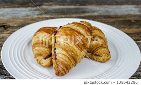 Three croissants sit on a white plate, ready to be enjoyed Three croissants sit on a white plate, ready to be enjoyed 138642286