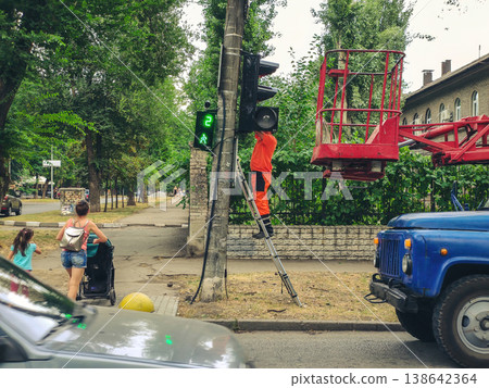 Worker of electric service company repair traffic lights in the city. Installation of a traffic light in the city. Worker of electric service company repair traffic lights in the city. Installation of a traffic light in the city. 138642364