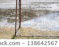 The dilapidated schoolyard of a closed elementary school. Puddles on the field after the rain, and the remaining soccer goal. A winter scene. 138642567