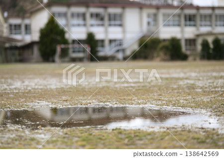 一所廢棄小學的破敗操場。雨後,操場上積滿了水窪,只剩下殘存的足球門。冬日景象。 一所廢棄小學的破敗操場。雨後,操場上積滿了水窪,只剩下殘存的足球門。冬日景象。 138642569
