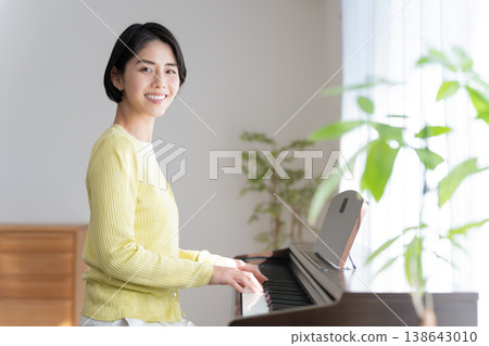 一位女士在家彈奏電子鋼琴 一位女士在家彈奏電子鋼琴 138643010
