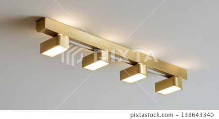 Modern ceiling with sleek golden metal track lights. Spot lighting led system. Closeup Room spotlights for interior design, commercial illumination. Minimalist white surface. Contemporary ambiance Modern ceiling with sleek golden metal track lights. Spot lighting led system. Closeup Room spotlights for interior design, commercial illumination. Minimalist white surface. Contemporary ambiance 138643340