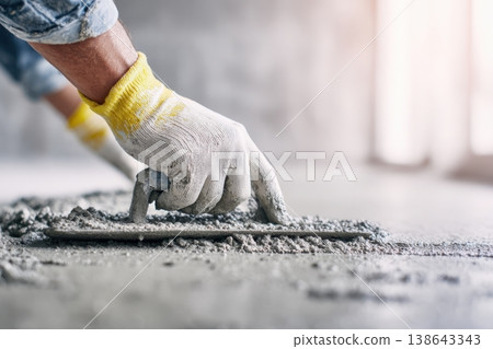 Mason using tool to level freshly poured grey concrete screed. Construction site of building pouring cement. Self Leveling wet mortar for floors. Master plasterer renovation home banner. Close-up hand Mason using tool to level freshly poured grey concrete screed. Construction site of building pouring cement. Self Leveling wet mortar for floors. Master plasterer renovation home banner. Close-up hand 138643343