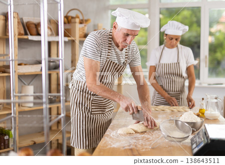 Elderly man and woman cutting and braiding dough 138643511