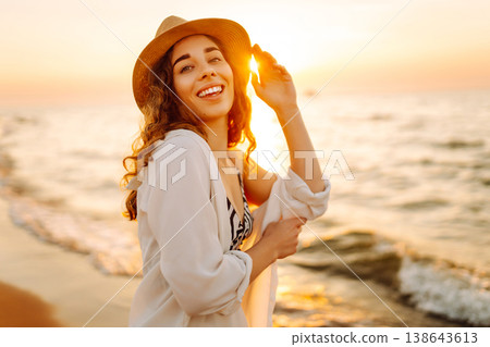 Carefree woman tourist walking along ocean sandy beach at sunset. Travel, weekend, lifestyle concept Carefree woman tourist walking along ocean sandy beach at sunset. Travel, weekend, lifestyle concept 138643613