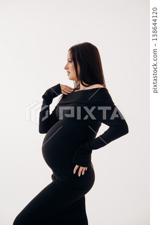 Pregnant woman posing in a stylish black outfit Pregnant woman posing in a stylish black outfit 138644120