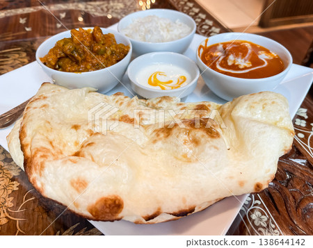 Vegetable curry and chicken masala curry. A lunch plate with a large naan bread and rice. Vegetable curry and chicken masala curry. A lunch plate with a large naan bread and rice. 138644142