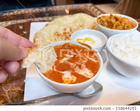 Chicken masala curry, made by simmering chicken and spices. The image shows people eating it with naan bread. Chicken masala curry, made by simmering chicken and spices. The image shows people eating it with naan bread. 138644201