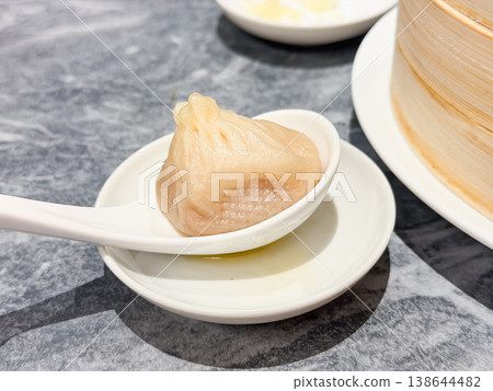 Steamed dishes. Delicious xiao long bao (soup dumplings) filled with plenty of juicy meat, eaten with a spoon. 138644482